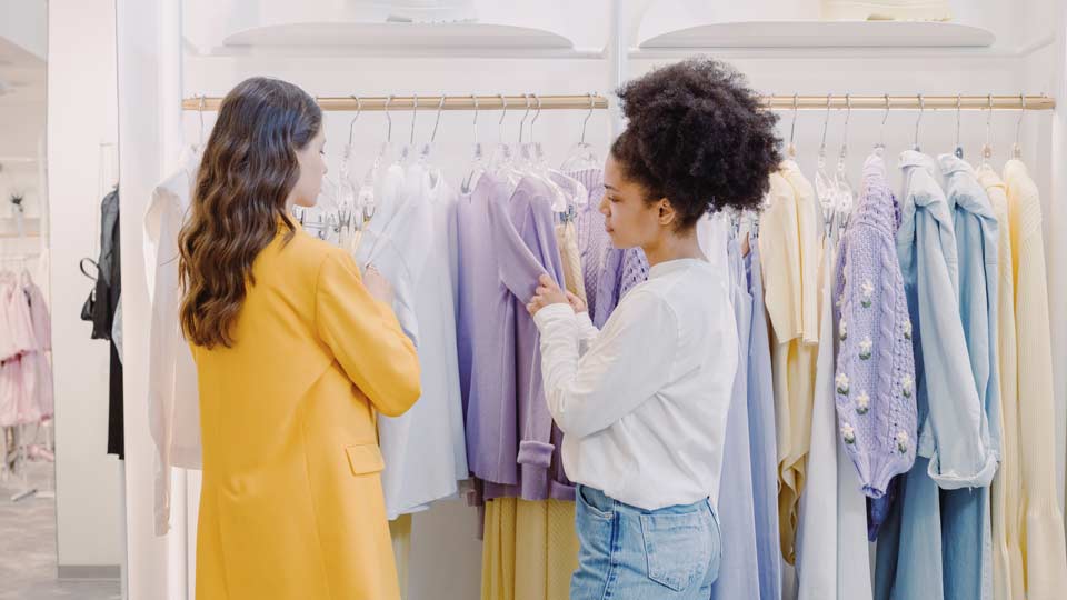 Zwei Frauen, die in der Modebranche arbeiten, vor einem Kleiderständer
