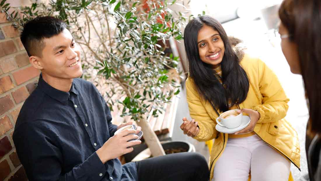 Drei Studierende unterhalten sich bei einem Kaffee